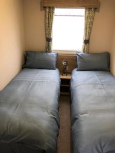 two beds in a small room with a window at Dunes Escape in Lossiemouth