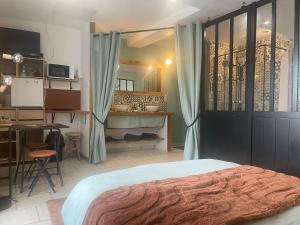 a bedroom with a bed and a desk and a kitchen at Le Cosy 8km du futuroscope in Beaumont