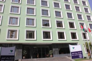 a green building with white windows and flags in front of it at Reef Al Malaz International Hotel by Al Azmy in Riyadh