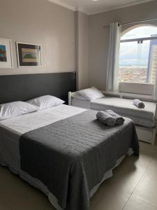 two beds in a hotel room with a window at Suíte Aconchegante in Belém