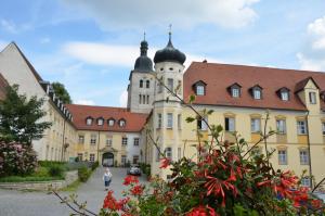 a large yellow building with a clock tower at Gäste- und Tagungshaus Benediktinerabtei Plankstetten in Berching +11 photos