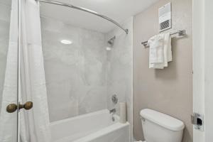 a white bathroom with a shower and a toilet at Ramada by Wyndham Temple Terrace/Tampa North in Tampa