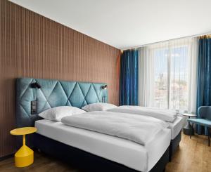 a bedroom with two beds and a blue headboard at H2 Hotel Erfurt in Erfurt