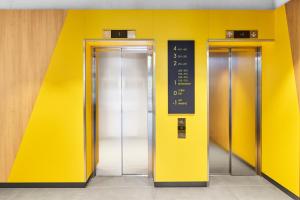 two elevators in a building with a yellow wall at H2 Hotel Erfurt in Erfurt