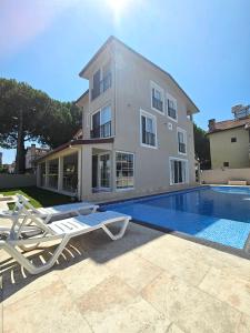 a house with a swimming pool and two lounge chairs at Luxury 5BR Villa w Pool & Beach Access Ayvalık in Ayvalık