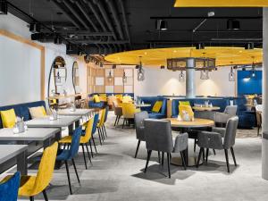 a dining room with tables and yellow chairs at H2 Hotel Erfurt in Erfurt