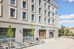 a building with tables and chairs in front of it at H2 Hotel Erfurt in Erfurt
