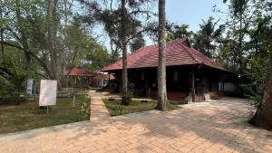 a building with a red roof in a park at Havmi Wellness Resort in Kumarakom