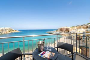 a table on a balcony with a view of the ocean at Del Mar Court in Marsalforn