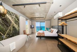 a bedroom with a tub and a bed with a view of the ocean at Del Mar Court in Marsalforn