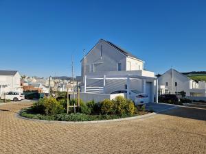 a white house with a car parked in a driveway at Casa Voliere in Stellenbosch