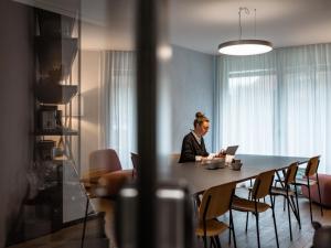 a woman sitting at a table with a laptop at b20 - serviced apartments bern ag in Bern +4 photos