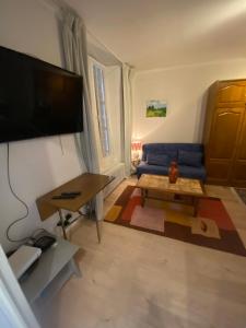 a living room with a blue couch and a tv at Appartement Kylie in Néris-les-Bains