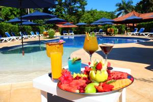 a tray of fruit and drinks on a table near a pool at La Foresta Nature Resort in Quepos
