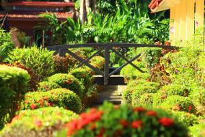 a small black bridge in a garden with flowers at La Foresta Nature Resort in Quepos