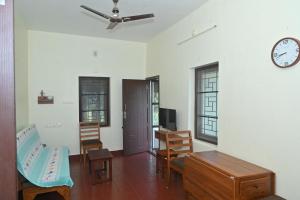 a living room with a ceiling fan and a clock on the wall at Nisarga Greens in Chittūr