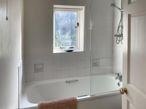 a white bathroom with a tub and a window at Whispering Pines - Uk51248 in Swyre