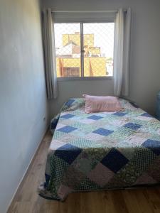 a bedroom with a bed with a quilt and a window at Quarto Privado em Apto Bigorrilho in Curitiba