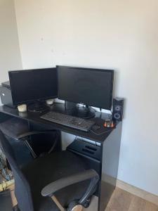 a desk with two computer monitors and a keyboard at Quarto Privado em Apto Bigorrilho in Curitiba