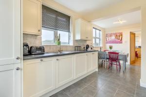 a kitchen with white cabinets and a dining room with a table at 2 Bed in Wem oc-o30240 in Preesgreen