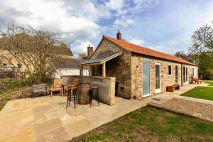 a patio with a grill and a house at Finest Retreats - The Den in Stamford