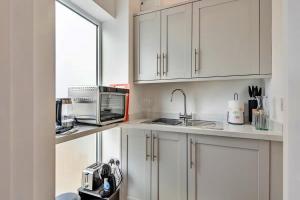a kitchen with white cabinets and a sink and a microwave at Finest Retreats - The Den in Stamford