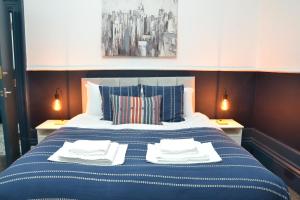 a blue and white bed with two towels on it at Manchester Ashton Suites in Ashton under Lyne