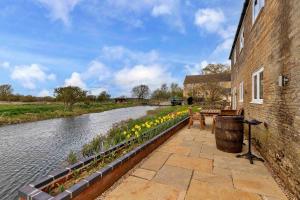 a brick building with benches and flowers next to a river at Finest Retreats - The Warren in Stamford