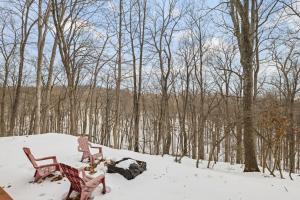 two chairs sitting in the snow next to trees at Pet-Friendly w Fire Pit Grill & Resort Access in Hedgesville