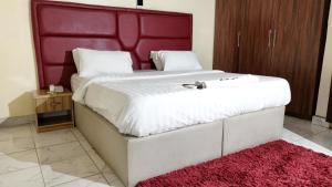 a bedroom with a large white bed with a red headboard at GTKATE Paradise Hotel in Ikeja