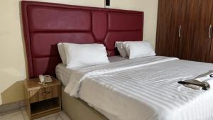 a bedroom with a large bed with a red headboard at GTKATE Paradise Hotel in Ikeja +4 photos