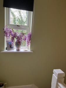 a vase of purple flowers sitting on a window sill at 18 Wixon Path in Buckinghamshire