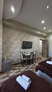 a hotel room with two beds and a table with chairs at Hotel New Royal in Tbilisi City