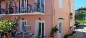a pink building with balconies and a street at Apartments Elena in Kavos