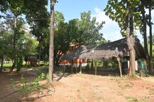 a hut with a thatched roof and some trees at Nisarga Greens in Chittūr