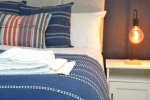 a bed with blue and white pillows and a lamp at Manchester Ashton Suites in Ashton under Lyne +39 photos