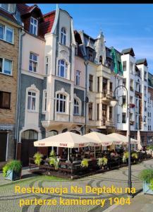 a building with tables and umbrellas in front of it at 1904 Studio in Świnoujście