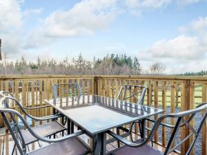 a table and chairs on a deck with a fence at The Orchard - Uk7111 in Alloa