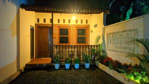 a house with potted plants in front of a door at Mudhia Homestay in Magelang +2 photos