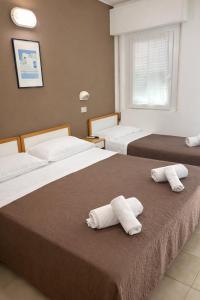 dwa łóżka w pokoju hotelowym z ręcznikami na nich w obiekcie Hotel Adria Mare w Rimini