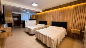 two beds in a room with wooden walls at Matrix Alojamiento in Punta Negra