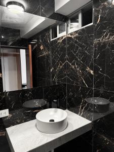 a bathroom with a white sink and a black wall at Matrix Alojamiento in Punta Negra