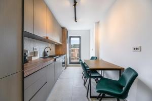a kitchen with a wooden table and green chairs at KOA - Signature Collection in Braşov