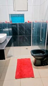 a bathroom with a black toilet and a red rug at Sonho de verão in Guarulhos +15 photos