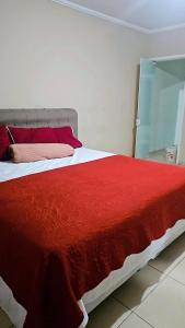 a bedroom with a bed with a red blanket at Sonho de verão in Guarulhos