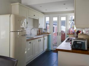 a kitchen with white cabinets and a white refrigerator at Gullsway in Beadnell