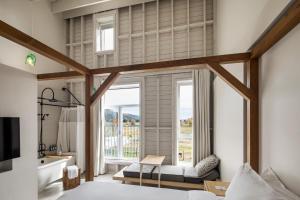 a bedroom with a large window and a bathroom with a tub at Hôtel & Spa Le Germain Charlevoix in Baie-Saint-Paul
