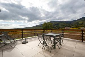 a table and chairs on a balcony with mountains at Gîte La perle d’Alsace in Bernardswiller +7 photos
