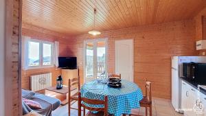 a room with a table and a kitchen with a refrigerator at Chalet de la Gougère 1 in Chambon-sur-Lac