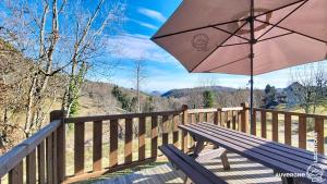 a wooden deck with a bench and an umbrella at Chalet de la Gougère 1 in Chambon-sur-Lac